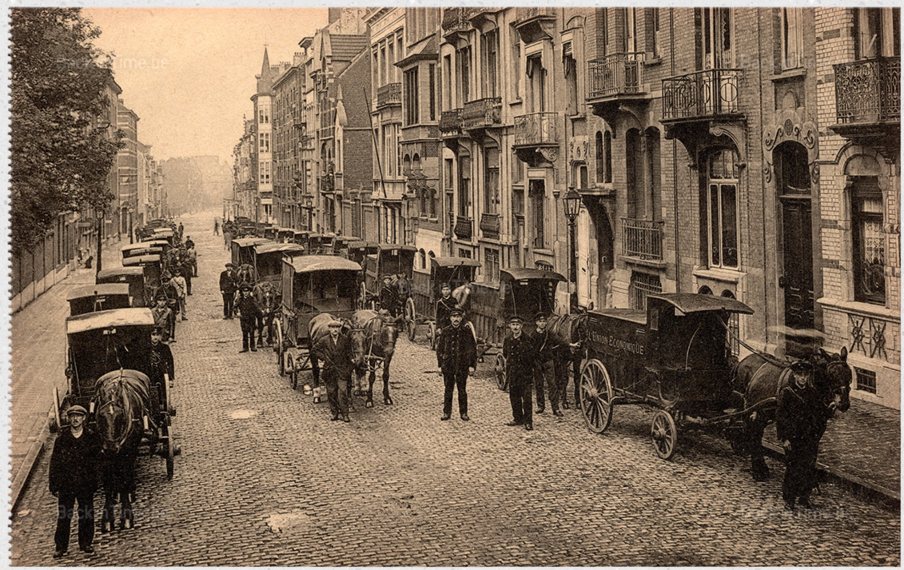 Carte postale ancienne : les voitures de livraison de l'Union Économique alignées dans une rue de Schaerbeek